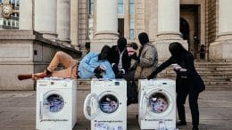 protesters sit on top of washing machines full of money