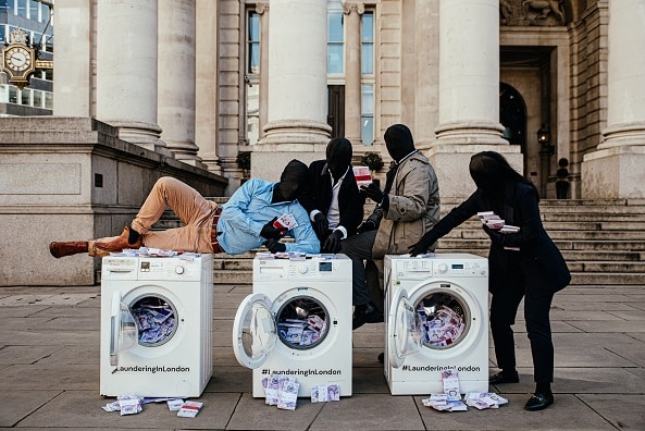 protesters sit on top of washing machines full of money