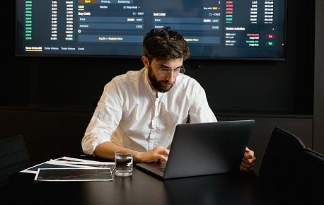 Man at laptop in front of a screen