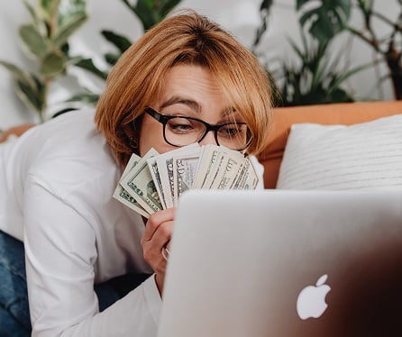 woman with cash looking at PC