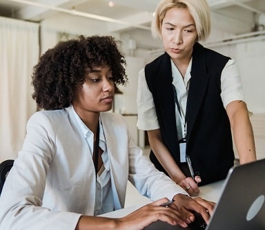 woman supervising younget employee on keyboard