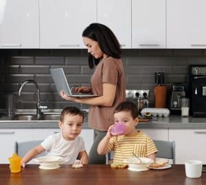 woman working on laptop in front of her children