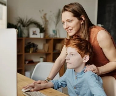 Young boy demonstrates his PC skills while his mother watches