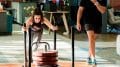 trainer watches girl pushing weights