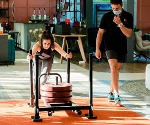 trainer watches girl pushing weights